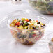 A close-up of two Sabert clear plastic containers filled with salad and vegetables.