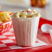 A white Genpak paper cup filled with macaroni and cheese on a red tray.