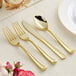 A Visions Classic gold plastic fork, spoon, and knife set on a table.