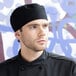 A man wearing a black Uncommon Chef mesh top chef hat with a hook and loop closure.