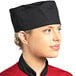 A woman wearing a black Uncommon Chef skull cap on a professional kitchen counter.