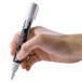 A close-up of a hand holding a Deflecto white marker with a white tip.
