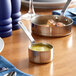 A Vollrath stainless steel saucepan filled with sauce on a table.