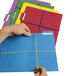 A hand holding a file folder with lime green rubber bands around colorful papers.
