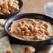 A bowl of hummus with chickpeas and pita bread.