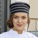 A woman wearing a Uncommon Chef chalk stripe chef hat.