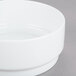 An Arcoroc white porcelain bowl on a gray surface.