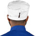 A man wearing a white Uncommon Chef skull cap with a white band and blue trim.