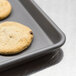 A Merrychef HardCoat quarter-size sheet pan with a chocolate chip cookie on it.
