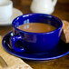 A cobalt blue Tuxton saucer with a cup of coffee on it.