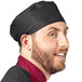 A man wearing a black Uncommon Chef skull cap at a deli counter.
