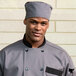 A man in a grey chef uniform wearing a slate grey Uncommon Chef skull cap.