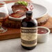 A bottle of Nielsen-Massey Madagascar Bourbon Vanilla Extract next to a plate of ribs.