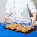 A chef holding a Cal-Mil rectangular tray cover over pastries on a counter.