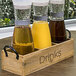 A wooden tray with glass jars of clear liquid, each with a Front of the House Drinkwise label.