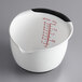 An OXO white measuring cup with red lines and text.