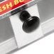 A close-up of a black round knob on a clear box.