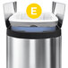 A white simplehuman trash can with a white custom fit liner with a yellow circle and the letter e.