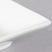 A close-up of a CAC Citysquare bright white square porcelain bowl on a white plate.