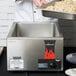 A chef using a Vollrath Nitro countertop food rethermalizer to prepare food in a large pan.