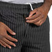 A person zipping up black and white pinstripe Uncommon Chef pants.