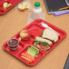 A Carlisle red 6 compartment tray with a sandwich, apple, carrot, and apple juice.