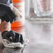 A gloved hand using an Advantage Chemicals orange spray bottle to clean a counter.