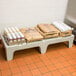 A Cambro solid top bow tie dunnage rack on a table with brown bags of food and a white bag with blue text on it.