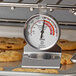 A Comark hot holding thermometer on a rack of cookies.