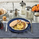 A Tablecraft blue enamelware plate with pancakes, bacon, and eggs on a table.