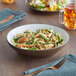 An Acopa Embers hickory brown stoneware pasta bowl filled with pasta, shrimp, and asparagus on a table with a fork.