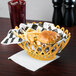 A yellow oval plastic fast food basket filled with a burger and fries on a table.