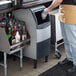 A person standing next to a Scotsman undercounter flake ice machine.
