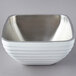 A Vollrath pearl white metal bowl with a silver rim.