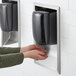 A person using a black Lavex stainless steel automatic hand dryer.