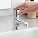 A hand pressing a Waterloo deck-mounted metering faucet.