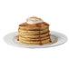 A stack of Krusteaz sweet potato pancakes with syrup and whipped cream on top.