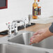 A person using a Waterloo deck-mounted faucet to wash their hands in a kitchen sink.