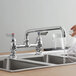A hand pouring water from a Waterloo deck-mounted faucet into a sink.