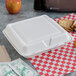 A white Dart foam takeout container with food on a checkered tablecloth.