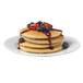 A stack of pancakes with berries and syrup on top.
