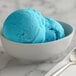A bowl of blue Italian ice with a spoon.
