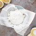 A yellow bowl with white cheesecloth covering a bowl of cream cheese and lemons.