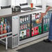 A man standing at a refrigerated counter full of drinks.