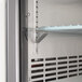 The inside of an Avantco black back bar refrigerator with metal shelves.
