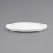A close up of a Front of the House Harmony bright white porcelain platter with a rim on a gray surface.