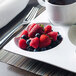 A Front of the House Harmony porcelain plate with berries and a cup of coffee.