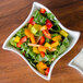 A close up of a white American Metalcraft Squavy bowl filled with a salad with yellow and orange vegetables.