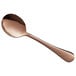 A close-up of an Acopa Vernon rose gold bouillon spoon with a rose gold handle.