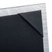 A Menu Solutions Alumitique aluminum table tent with black leather corners on a table.